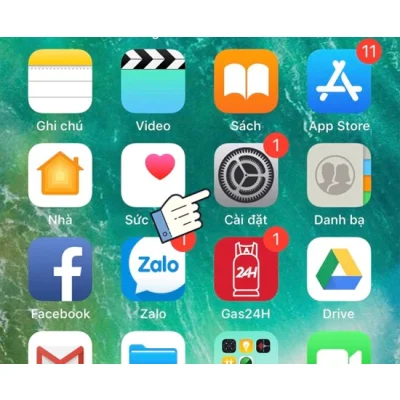 Màn hình điện thoại iPhone hiển thị ứng dụng, con trỏ tay chỉ vào Cài đặt, hướng dẫn chi tiết tại Kim Anh Mobile Đà Nẵng.